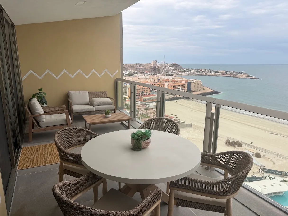 The view from a high balcony in Puerto Peñasco, looking over the beach and the water with outdoor furniture in front