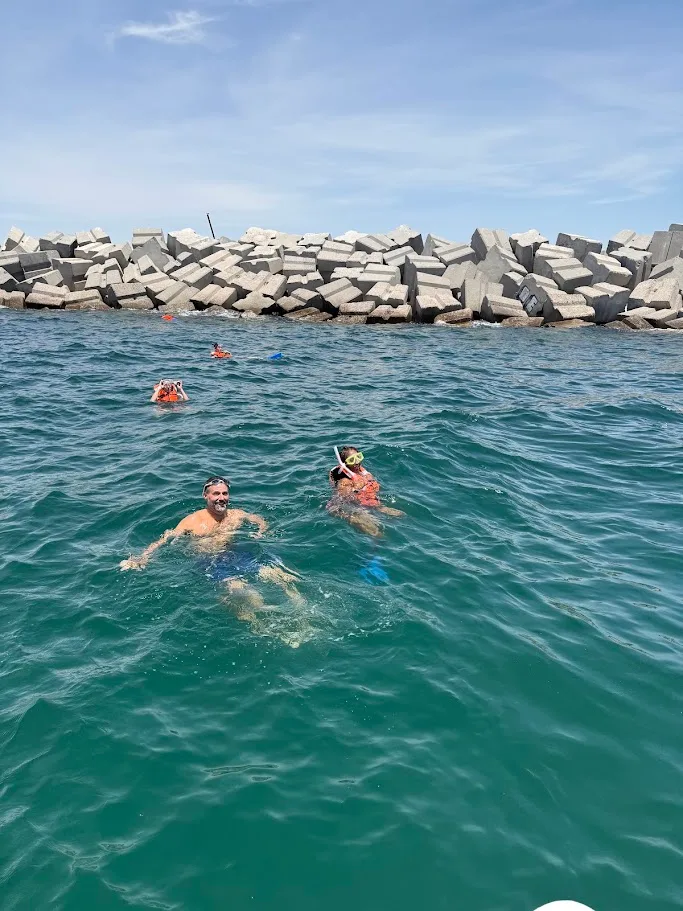 Two of us snorkeling in the Sea of Cortez with a rock breakwater behind us
